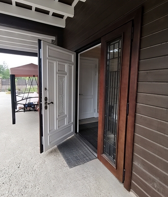 Парадная дверь с резьбой, стеклом и ковкой в коттедж – пример работы в июле